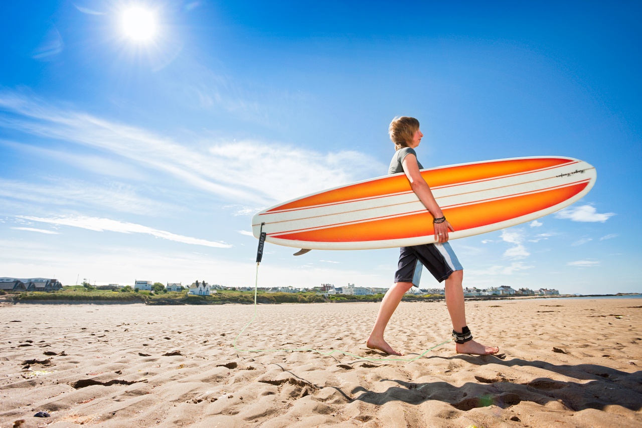 Woman carrying surfboard on beachSurfing Rhosneigr Anglesey North Activities And Sports