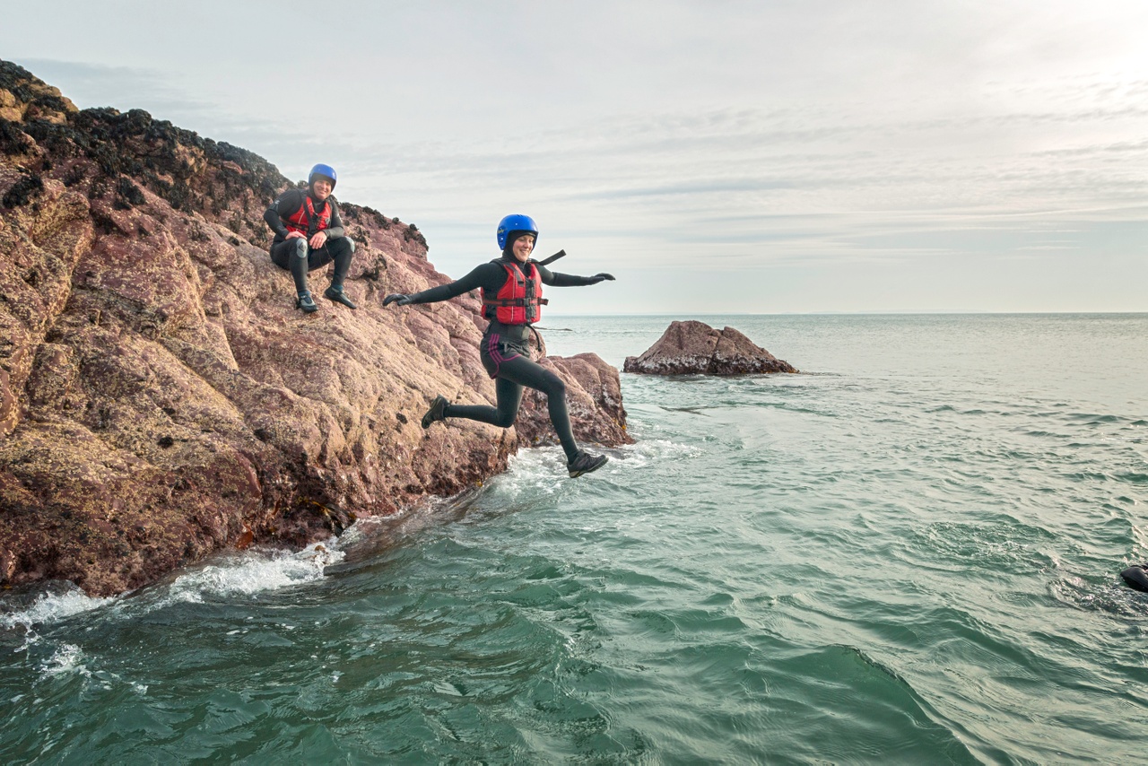 Coasteering in Wales Person jumping off a rock into the sea