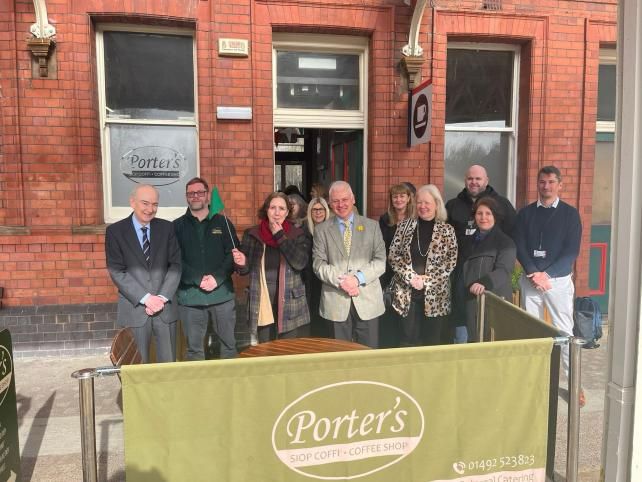 Group of people standing in front of 'Porter's' coffee shop entrance smiling for a photo.